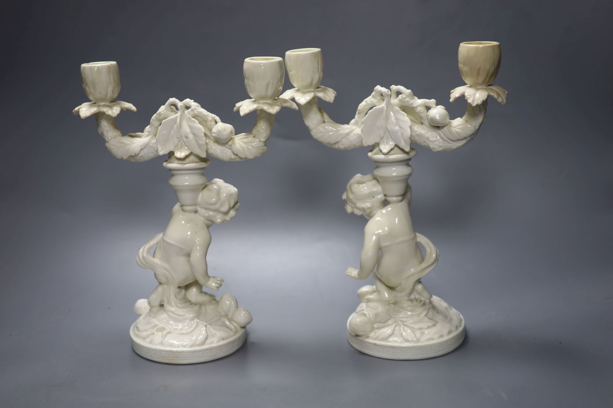 A pair of English bone china cherub candelabra, possibly Moore Bros., height 26cm